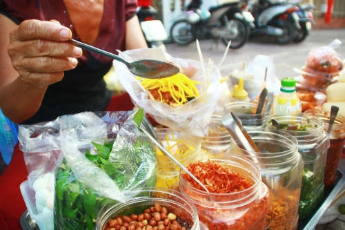 Nói đến món ăn vặt "tủ" của học sinh Sài Gòn, khó có thể bỏ qua bánh tráng trộn với sự kết hợp giữa bánh tráng và gần mười nguyên liệu gồm bò khô, gan xào, xoài xanh, đậu phộng… Tất cả cùng tạo ra hương vị chua, cay, mặn, ngọt không lẫn vào đâu. Không ai có thể nói món ăn vặt này bán ở đâu ngon nhất nhưng nếu muốn nếm một bịch bánh tráng trộn với nước bò đậm đà đúng nghĩa, bạn có thể ghé cổng trường THCS Minh Đức, quận 1. mon-an-vat-truoc-cong-truong-cua-hoc-sinh-sai-gon-ivivu-1