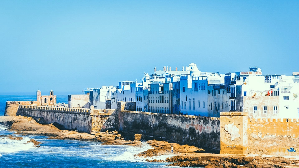 Bức họa về Morocco sẽ thật thiếu sót nếu thiếu đi thành phố Essaouira, vùng đất màu xanh đại dương, nằm ở điểm cực Tây của đất nước. Nơi đây thuở trước là một làng chài. Bạn có thể ghé thăm Medina, khu phố cổ như một chợ không mái che khổng lồ mà mỗi ngôi nhà trong những ngõ nhỏ là một sạp hàng hóa. Chiều về, khi ánh hoàng hôn chìm dần, tôi đi dạo ra phía cảng cá, ngắm đàn hải âu dạn dĩ bay rạp người, hít một hơi dài, cảm nhận vị mằn mặn của biển nhờ gió đưa vào từ xa.