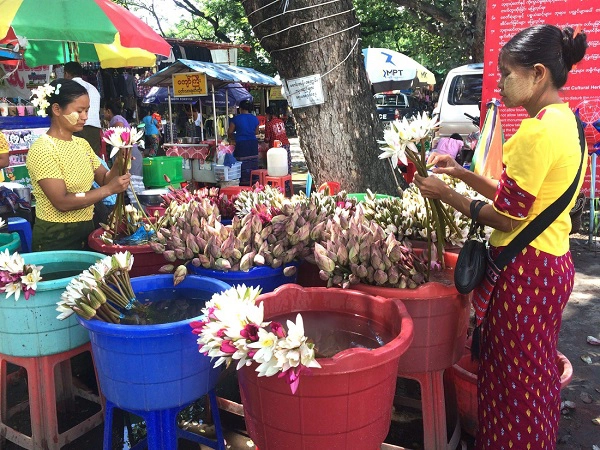 Trước cổng chùa, những người phụ nữ Myanmar chăm chút từng cánh hoa để bán cho khách viếng chùa, trên má ửng màu của nắng, điểm xuyến họa tiết của bột dưỡng da Thanaka - Ảnh: Bông Mai