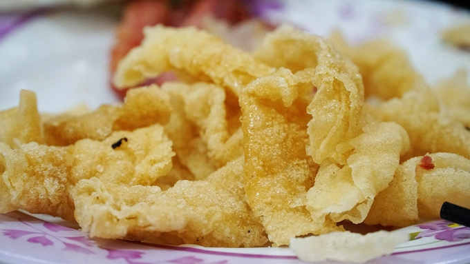 Đồ ăn kèm nem nướng còn có bánh tráng chiên. Những miếng bánh giòn rụm có màu vàng bắt mắt nhưng hơi ngấy mùi dầu ăn.