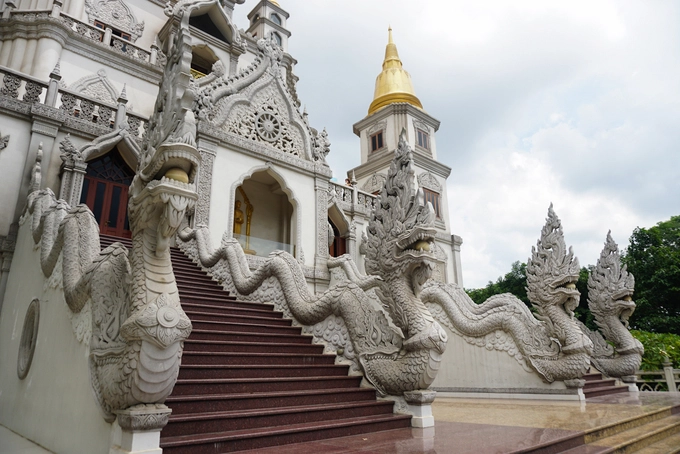 Cạnh hồ nước là lối lên bảo tháp, du khách phải bỏ dép ở dưới sân nếu muốn lên các tầng lầu. Xung quanh lối lên là linh vật rồng ngậm ngọc uốn lượn cùng mây. Kiến trúc của chùa mang nét Phật Giáo Nam Tông đặc trưng trong vùng Đông Nam Á, với các họa tiết trang trí như rồng uốn lượn tạo thành mái vòm, hoa văn nổi, phù điêu, bánh xe chuyển pháp luân,... Cạnh hồ nước là lối lên bảo tháp, du khách phải bỏ dép ở dưới sân nếu muốn lên các tầng lầu. Xung quanh lối lên là linh vật rồng ngậm ngọc uốn lượn cùng mây. Kiến trúc của chùa mang nét Phật Giáo Nam Tông đặc trưng trong vùng Đông Nam Á, với các họa tiết trang trí như rồng uốn lượn tạo thành mái vòm, hoa văn nổi, phù điêu, bánh xe chuyển pháp luân,...
