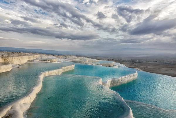 <strong>Pamukkale, Denizli, Thổ Nhĩ Kỳ: </strong>Pamukkale dịch ra có nghĩa là “Lâu đài bông”. Tên gọi này xuất phát từ màu trắng huyền ảo của những bờ đá hình thành do suối nước nóng ở miền Tây Nam Thổ Nhĩ Kỳ. Được coi là báu vật quốc gia, nơi này được bảo vệ chặt chẽ, nhưng du khách vẫn được phép xuống ngâm mình trong những hồ nước nhỏ và nông này. Ảnh: Ibellhop. <strong>Pamukkale, Denizli, Thổ Nhĩ Kỳ: </strong>Pamukkale dịch ra có nghĩa là “Lâu đài bông”. Tên gọi này xuất phát từ màu trắng huyền ảo của những bờ đá hình thành do suối nước nóng ở miền Tây Nam Thổ Nhĩ Kỳ. Được coi là báu vật quốc gia, nơi này được bảo vệ chặt chẽ, nhưng du khách vẫn được phép xuống ngâm mình trong những hồ nước nhỏ và nông này. Ảnh: Ibellhop.