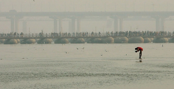 Một người hành hương lấy nước sông để tắm gội trong lễ hội Kumbh Mela, phía sau là hàng nghìn người vẫn đang di chuyển về nơi họ tin sẽ rửa sạch mọi tội lỗi của bản thân. Ảnh: Mario Tama.