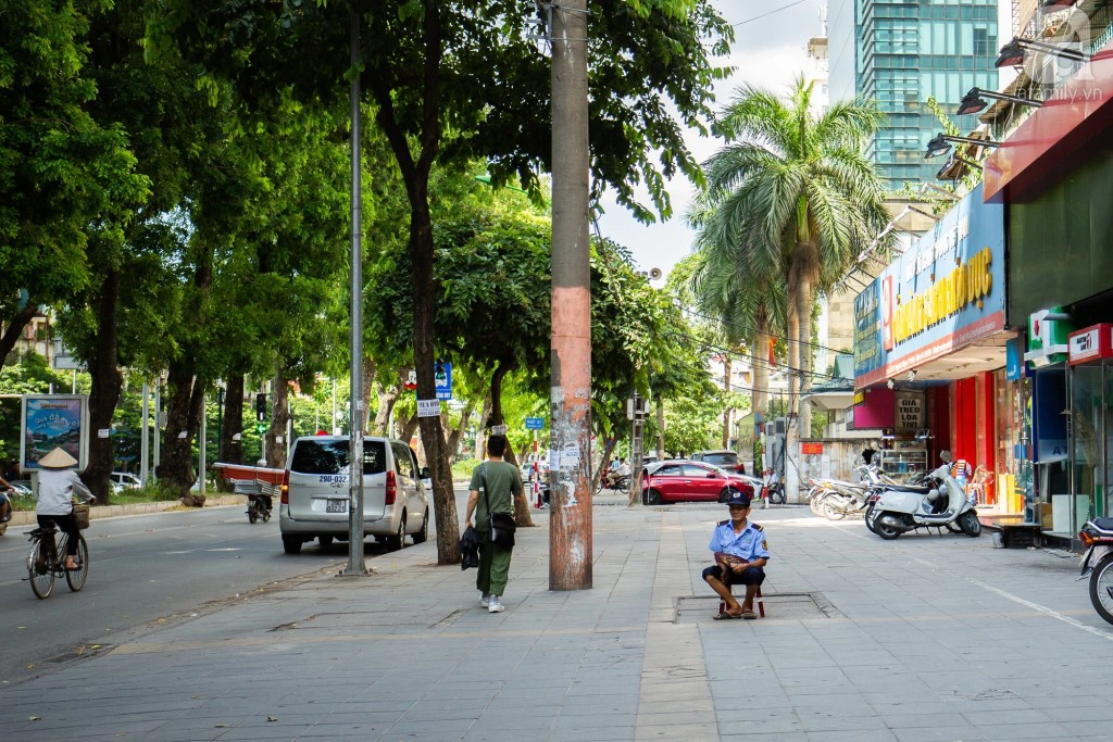 Những bác xe ôm, bảo vệ thong dong ngồi dưới gốc cây, giữa vỉa hè với chiếc quạt nan phe phẩy gió trời.