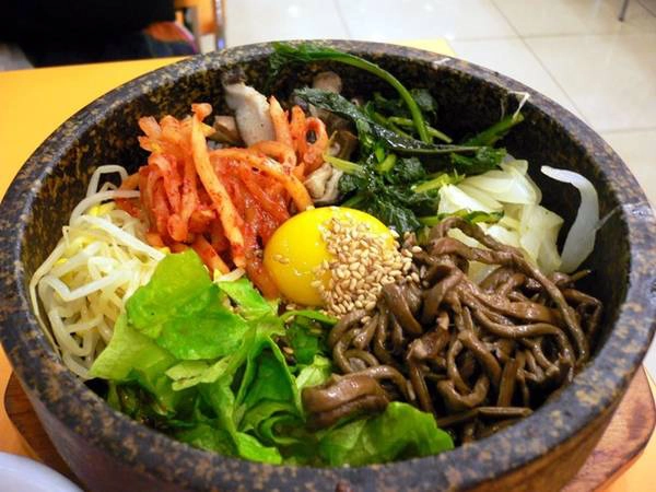 Bibimbap gồm cơm, các loại rau củ, thịt, trứng với tương ớt và dầu mè, được trộn đều và dọn ra trên bát đá nung nóng.