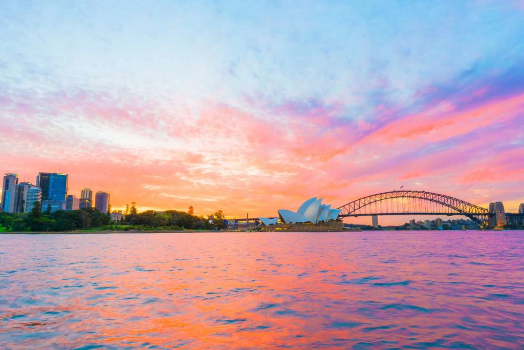 Sydney (Australia): Opera Syney hay "nhà hát con sò" trở nên nổi bật dưới ánh hoàng hôn. Các công trình kiến trúc hiện đại phản chiếu xuống mặt nước nhuốm màu cam, tím, tạo nên khoảnh khắc cuối ngày ấn tượng.