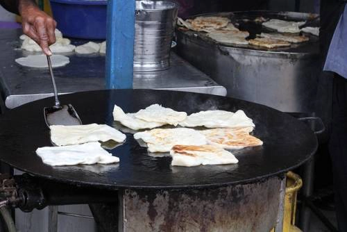 Roti Canai Roti Canai là bánh mì dẹt, du khách dễ thấy hàng bánh này ở Jalan Transfer, một khu phố ẩm thực của George Town. Món này thường ăn với cà ri như một bữa sáng. Quầy roti canai thường có hai đầu bếp, một người lấy bột nhào, người còn lại cho bột lên rán trên chảo lớn. Trông họ chế biến món ăn bạn sẽ liên tưởng tới những tay chơi trống thực thụ. 