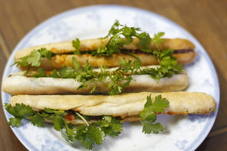 Bánh mì cay Hải Phòng Du nhập lên Hà Nội cách đây khoảng chục năm, những chiếc bánh mì của đất cảng nhanh chóng trở thành món ăn quen thuộc của người dân Hà thành. Mỗi khi có khách tới mua, chủ hàng nướng lại những chiếc bánh nhỏ xíu, cho patê vào bên trong, thêm chút chí chương (tương ớt) giúp kích thích vị giác. Mỗi người có thể ăn 3-4 chiếc với giá khoảng 10.000 - 15.000 đồng. Bánh mì cay Hải Phòng thường không ăn với rau mùi, nhưng bạn có thể cho thêm nếu thích. Ảnh: Út Liên. Bánh mì cay Hải Phòng Du nhập lên Hà Nội cách đây khoảng chục năm, những chiếc bánh mì của đất cảng nhanh chóng trở thành món ăn quen thuộc của người dân Hà thành. Mỗi khi có khách tới mua, chủ hàng nướng lại những chiếc bánh nhỏ xíu, cho patê vào bên trong, thêm chút chí chương (tương ớt) giúp kích thích vị giác. Mỗi người có thể ăn 3-4 chiếc với giá khoảng 10.000 - 15.000 đồng. Bánh mì cay Hải Phòng thường không ăn với rau mùi, nhưng bạn có thể cho thêm nếu thích. Ảnh: Út Liên.