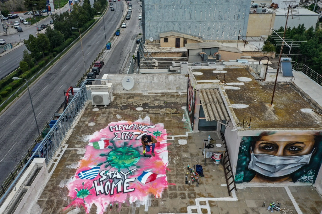 Trên nóc chung cư tại Athens, Hy Lạp, một nghệ sĩ 16 tuổi đang thực hiện tác phẩm phun sơn rực rỡ, thông điệp "Hãy ở nhà" để chống dịch Covid-19 được thể hiện nổi bật.