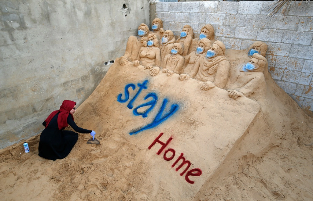 Nghệ sĩ Rana al-Ramlawi đang tạo ra một tác phẩm điêu khắc cát ở thành phố Gaza, Palestine. Thông điệp "Stay Home" nhằm kêu gọi mọi người "Hãy ở yên tại nhà" trong mùa dịch.