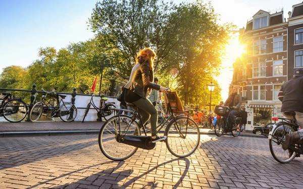Amsterdam, Hà Lan: Được mệnh danh là thành phố xe đạp nhiều hơn người, Amsterdam là một trong những nơi thích hợp để đạp xe nhất trên thế giới. Hệ thống đường xá an toàn, thuận tiện, sự ủng hộ của chính phủ và văn hóa xe đạp xóa nhòa khoảng cách xã hội là lý do tới hơn 40% người dân sống ở Amsterdam di chuyển bằng xe đạp. Với du khách, việc thong thả đạp xe qua những con phố và kênh đào xinh đẹp là một trải nghiệm khó quên. Ảnh: Roughguides. Amsterdam, Hà Lan: Được mệnh danh là thành phố xe đạp nhiều hơn người, Amsterdam là một trong những nơi thích hợp để đạp xe nhất trên thế giới. Hệ thống đường xá an toàn, thuận tiện, sự ủng hộ của chính phủ và văn hóa xe đạp xóa nhòa khoảng cách xã hội là lý do tới hơn 40% người dân sống ở Amsterdam di chuyển bằng xe đạp. Với du khách, việc thong thả đạp xe qua những con phố và kênh đào xinh đẹp là một trải nghiệm khó quên. Ảnh: Roughguides.