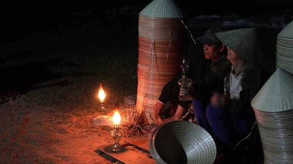 Người bán dùng ánh sáng đèn dầu đỏ và ấm nên không bị lóa, người mua soi rõ được những đường kim, mũi cước trên từng chiếc nón. Người bán dùng ánh sáng đèn dầu đỏ và ấm nên không bị lóa, người mua soi rõ được những đường kim, mũi cước trên từng chiếc nón.