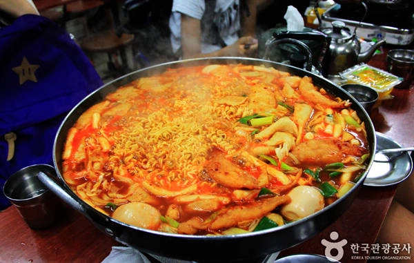 Ngay từ đầu phố, bạn đã có thể ngửi thấy mùi thơm ngào ngạt tỏa ra từ những chảo bánh gạo nghi ngút khói đang mời gọi. Nơi đây bán chủ yếu là tteokbokki ăn liền, tức là được nấu tại chỗ ăn kèm với nhiều loại rau, chả cá, mì và bánh bao… Bạn có thể ăn tại chỗ hoặc mua mang đi đều được. Điểm đặc biệt của món tteokbokki chính là phần nước sốt đặc biệt được làm từ bột đậu nành đen và ớt sa tế Hàn Quốc. Nhìn thì có vẻ rất cay nhưng thực chất lại chỉ hơi tê lưỡi, thậm chí còn có phần hơi ngọt.