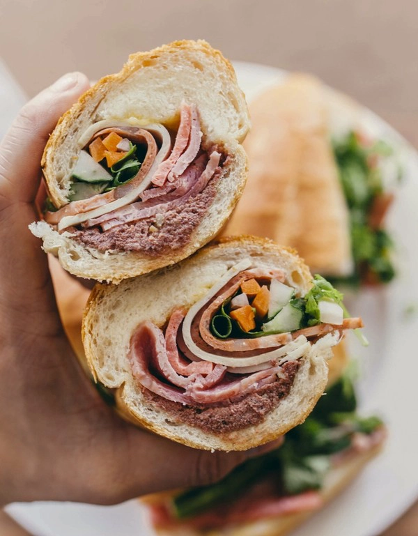 Bánh mì ở Cô Thành được nhiều thực khách quốc tế yêu thích bởi đầy đặn với đủ pate, thịt nguội, tương ớt, mayonnaise, rau thơm, dưa chuột. Thực khách muốn ăn bánh mì nên tới sớm để có thể đảm bảo bánh của mình nóng và giòn hơn. Ảnh: SCMP. Bánh mì ở Cô Thành được nhiều thực khách quốc tế yêu thích bởi đầy đặn với đủ pate, thịt nguội, tương ớt, mayonnaise, rau thơm, dưa chuột. Thực khách muốn ăn bánh mì nên tới sớm để có thể đảm bảo bánh của mình nóng và giòn hơn. Ảnh: SCMP.