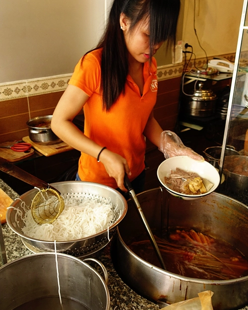 Quán ăn nằm trên đường Bùi Viện, quận 1. Theo chị Huỳnh Giao, chủ quán hiện tại, quán do ông bà của chị mở từ những năm 90 của thế kỷ trước, ban đầu chỉ bán trên gánh ở vỉa hè Sài Gòn. "Tất cả công thức đều được truyền từ ông bà đến cha mẹ và tôi", chị Giao cho hay. Các nguyên liệu như chả tôm, chả cua đều do quán tự làm. Trong hình là nhân viên bếp của quán. Ảnh: @auntierim_s. Quán ăn nằm trên đường Bùi Viện, quận 1. Theo chị Huỳnh Giao, chủ quán hiện tại, quán do ông bà của chị mở từ những năm 90 của thế kỷ trước, ban đầu chỉ bán trên gánh ở vỉa hè Sài Gòn. "Tất cả công thức đều được truyền từ ông bà đến cha mẹ và tôi", chị Giao cho hay. Các nguyên liệu như chả tôm, chả cua đều do quán tự làm. Trong hình là nhân viên bếp của quán. Ảnh: @auntierim_s.