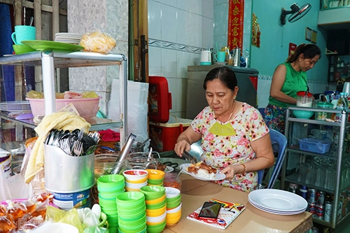 Một chiếc bàn gỗ được kê ở phía trước là nơi chuẩn bị món ăn cho khách. Chị Hà và mẹ (ảnh) thay nhau ngồi quầy. Ảnh: Di Vỹ.