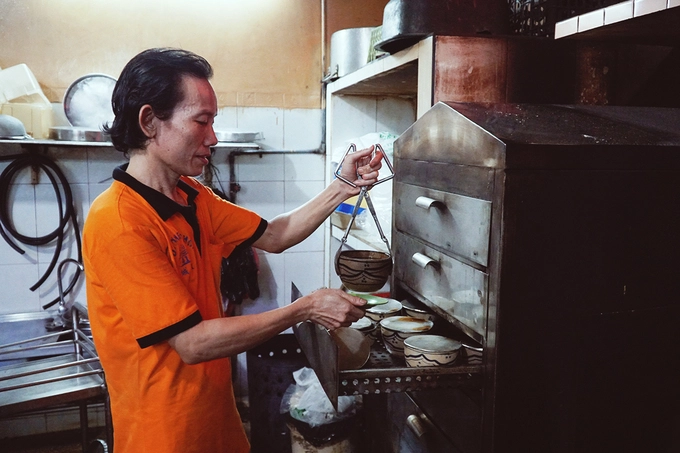 Một nhân viên gắp thố gà tiềm sau khi đã hâm nóng. Một nhân viên gắp thố gà tiềm sau khi đã hâm nóng.
