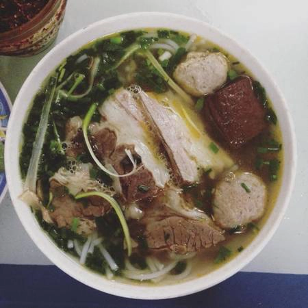 Bún bò Huế rất được ưa chuộng ở phố Quang Trung, trong đó được biết đến nhiều nhất là quán O Xuân với hơn 20 năm kinh nghiệm. Bát bún đầy đặn với móng giò, chả viên, tiết luộc, thịt bò thái miếng cùng nước dùng trong vắt; thêm chút hoa chuối thái sợi cùng rau sống chần qua. Giá một bát là 30.000 đến 50.000 đồng. Ảnh: Hà My.