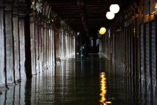 Du khách đứng trong dòng nước lụt làm ngập quảng trường Thánh Mark, ở Venice, 01/11/2012.