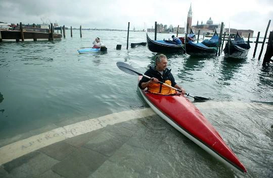 Một người đàn ông chèo thuyền kayak trước Piazza San Marco khi thuỷ triều dâng cao làm ngập Venice, 01/11/2012