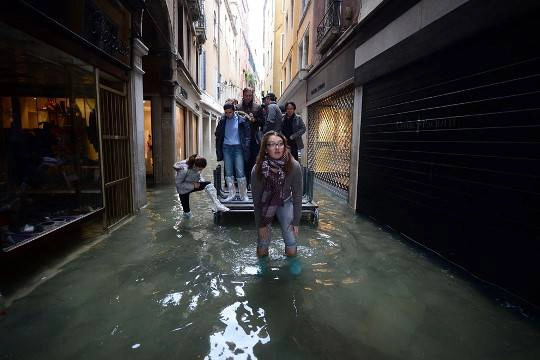 Mọi người di chuyển trên một con phố nhỏ bị ngập nước ở Venice, 01/11/2012