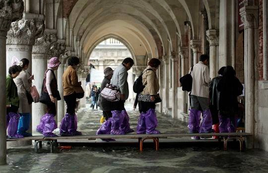 Khách du lịch mang ủng nilon đi trên chiếc cầu gỗ ở gần Piazza San Marco, 27/10/2012.