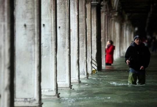 Một người đàn ông đi trong dòng nước trên con phố ở Venice, 11/11/2012