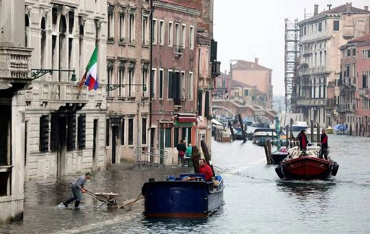 Một công nhân đẩy chiếc xe rùa qua dòng nước khi Venice vào “mùa nước nổi”, 27/10/2012.