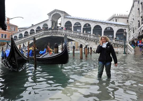 Một người phụ nữ bước đi trong dòng nước ở gần cầu Rialto, Venice, 01/11/2012.