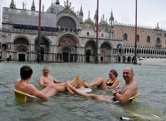 Bốn người ngồi quanh một chiếc bàn đặt trong dòng nước ở Piazza San Marco, Venice, 11/11/2012.