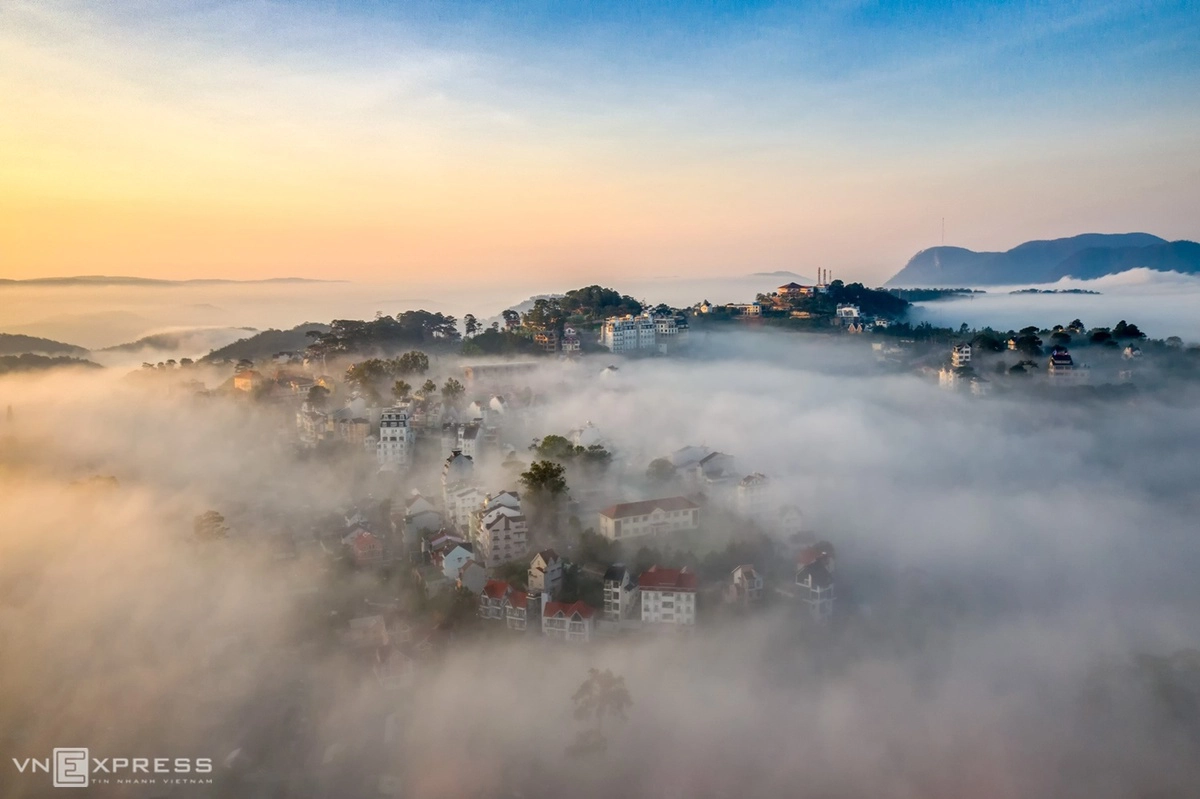 Một góc trung tâm phố núi huyền ảo trong sương sớm, phía xa là cáp treo trên đồi Robin Đà Lạt.  “Sương xuất hiện sau những cơn mưa đầu mùa vào cuối tháng 4. Săn sương phải chuẩn bị từ sáng sớm, lúc hừng đông vừa lên và kéo dài tới 7h sáng là lý tưởng”, anh Quang Anh cho biết.