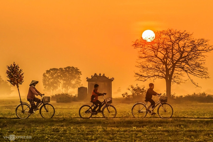 Người dân chở hoa giấy Tết ngang qua một miếu thờ bên ngoài làng Thanh Tiên.