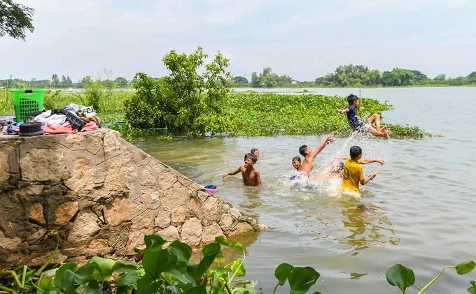 Trẻ em người Chăm nô đùa ở ven Búng Bình Thiên trong buổi trưa, phía trước thánh đường. Hồ nước là nơi diễn ra nhiều hoạt động của người dân địa phương, từ đánh bắt thuỷ sản đến tắm, giặt, vui chơi. Búng Bình Thiên và thánh đường Hồi giáo cách thành phố Châu Đốc khoảng 30 km về phía bắc, giáp biên giới Campuchia.