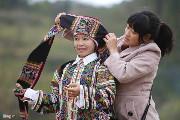 Cô gái người Lô Lô được chị vấn khăn trước khi du xuân. Em cho biết trang phục này phải thêu tay nhiều tháng mới xong, chỉ mặc trong những dịp lễ hội lớn,