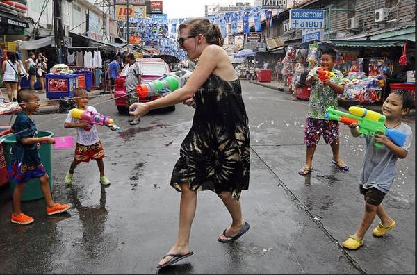 Một khách du lịch nước ngoài đang vui đùa với trẻ em Thái Lan trên đường Khao San trong lễ hội Songkran.