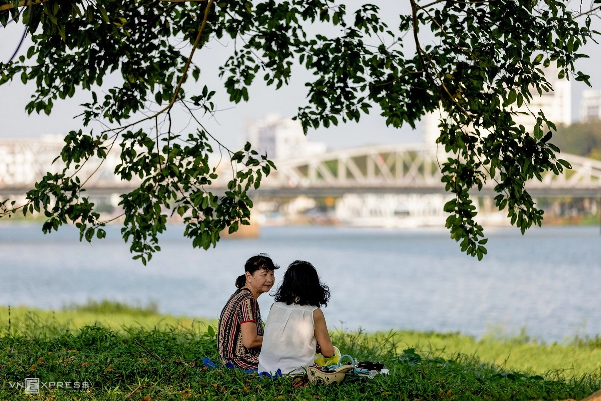   Hai phụ nữ trò chuyện tại công viên bên bờ sông Hương.  “Thật khó có thể dùng từ ngữ để diễn tả hết được vẻ đẹp trầm mặc và những điều bình dị nhất của vùng đất cố đô. Tôi sống và làm việc tại đây, dùng cảm xúc nhiếp ảnh để mang vẻ đẹp của vùng đất giới thiệu đến tất cả mọi người”, tác giả ảnh chia sẻ.