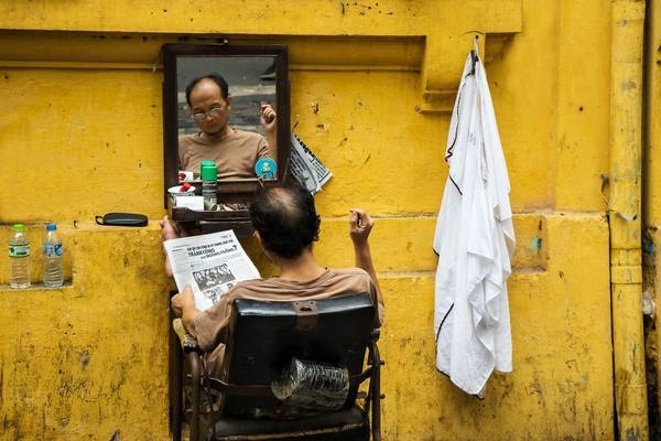Một mảng màu bình dị trong cuộc sống thường nhật ở thủ đô Hà Nội: người thợ cắt tóc chăm chú đọc báo trong lúc chờ khách hàng. Một mảng màu bình dị trong cuộc sống thường nhật ở thủ đô Hà Nội: người thợ cắt tóc chăm chú đọc báo trong lúc chờ khách hàng.