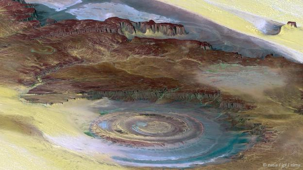 <strong>Mắt sa mạc Sahara, Mauritania: </strong> Tọa lạc trong sa mạc Sahara, nơi đây còn được biết với tên gọi “cấu trúc Richat”. Đó là một cấu trúc đá hình mái vòm, có đường kính khoảng 50 km, khi nhìn từ trên cao nó trông như một thấu kín bán cầu. Ban đầu, sự hình thành mắt sa mạc được cho là do tác động của thiên thạch. Nhưng các lý thuyết gần đây cho rằng đó thực chất là một sản phẩm của sự xói mòn địa chất theo thời gian.